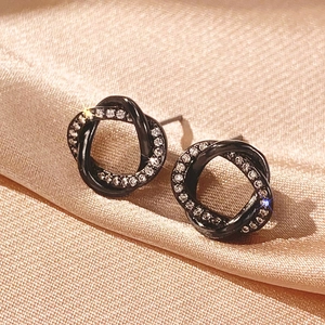 Detailed view of black metal twist hoop earrings with sparkling cubic zirconia inlay