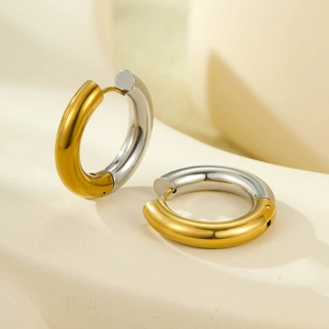 Macro detail of geometric C-shaped hoop earrings with gold and silver two-tone metal finish