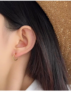 Detailed view of a gold textured hoop earring worn on an ear for a natural luxury style