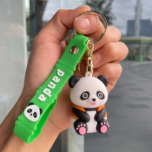 Close-up of cute panda doll keychain with green silicone panda wrist strap on a hand
