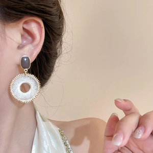 Gros plan de boucles d'oreilles bohèmes avec clous noir-or et pendentifs cercles tissés blancs