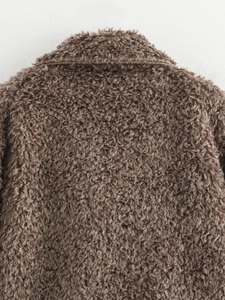 Close-up detail of dark brown faux lamb fur texture and stitching on fashion jacket