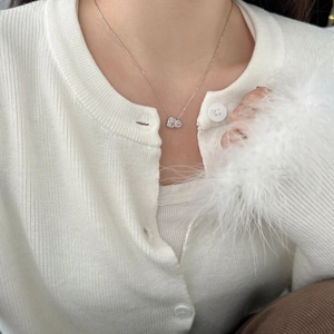 Detail of double heart pendant necklace with white zircons worn on female model's neck
