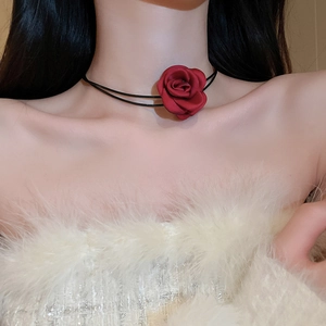 Close-up of red fabric rose necklace with double black cords worn on a model collarbone