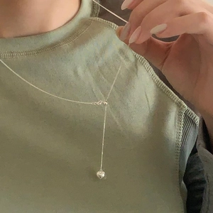 Close-up of minimalist silver heart pendant necklace on a delicate Y-shaped chain