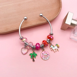 Silver open bangle with unicorn and donut charms on a soft pink decorative background