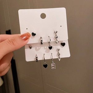 Detailed set of six minimalist black heart stud earrings and hoops on white card