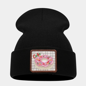 Detail of black knit beanie featuring a donut dessert embroidery patch with Cake text
