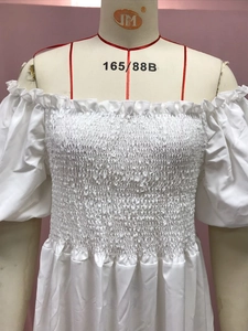 Detail of white off-shoulder smocked top featuring ruffled elastic cuffs and neckline