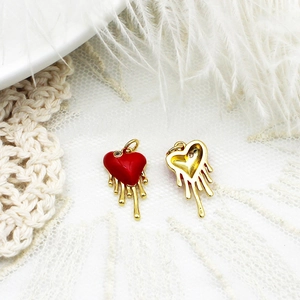 Detail of red oil drip heart pendants showing golden back on lace background