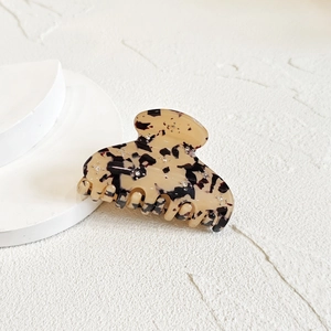 Detail view of tortoiseshell hair claw with sparkling rhinestones on a white background