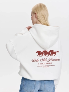 Oversize white fleece hoodie for women with red horse print on the back in a studio setting