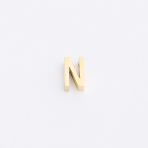 Detailed macro view of a 1.8mm gold-plated stainless steel letter N bead with mirror finish