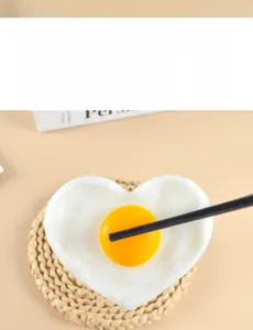Macro shot of heart-shaped fried egg model with orange yolk on a woven straw mat
