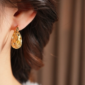 Macro shot of gold-plated woven drop earrings with intricate cross-braided texture