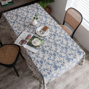Detail of blue floral rectangular tablecloth with tassel edges on a cotton linen blend fabric