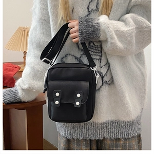 Detail of black nylon shoulder bag with white snap buttons and adjustable strap