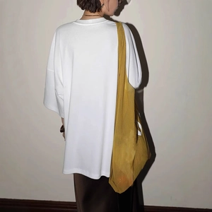 Detailed texture of an oversized white short-sleeved cotton T-shirt from a side back view