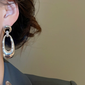 Detail of silver oval hoop earring with zircon inlay shown on model's ear profile