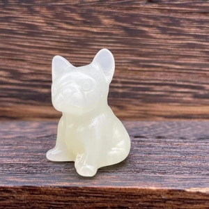 Macro shot of a 3cm white semi-transparent crystal French bulldog figurine on wood