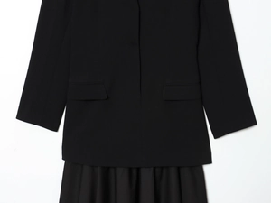 Detail van de zwarte triacetaat blazer met geplooide rokzoom en plat zakontwerp