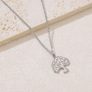 Detailed close-up of a silver-tone tree of life pendant on a delicate cross chain
