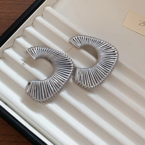 Close-up of silver semi-circular fan earrings with artistic woven wire texture