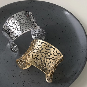 Modern wide hollow cuff bracelet in gold and silver finish with organic fluid texture