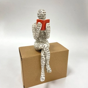 Macro detail of reading woman resin sculpture with black text print and red book