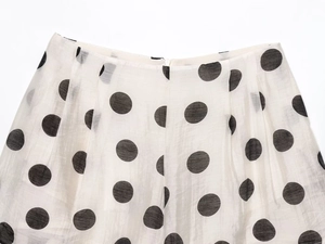 Detail view of the hidden zipper on a black and white polka dot skirt with vertical texture