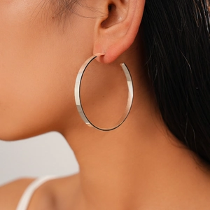 Close-up of a large silver geometric round earring with a polished metallic finish on a model