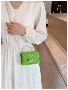 Macro detail of green quilted mini bag featuring pearl handle and gold chain strap