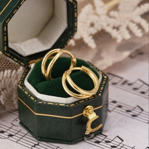 Detailed close-up of golden double-layer hoop earrings in a vintage green jewelry box