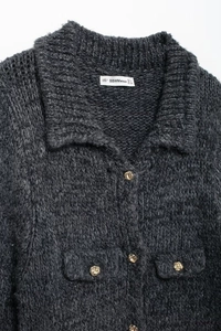 Détail du cardigan en maille gris foncé avec boutons dorés et deux petites poches avant