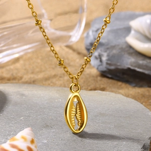 Golden shell pendant necklace on O-chain, displayed on stone with a beach vibe