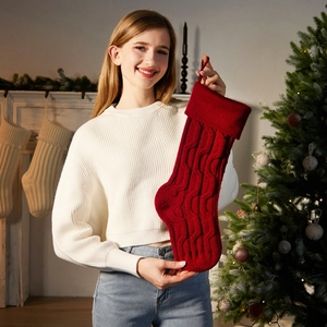 Classic red cable knit Christmas stocking hanging in a warm festive living room scene