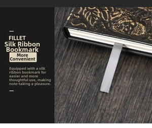 Close-up of embossed vintage notebook cover with a grey silk ribbon bookmark and wood background