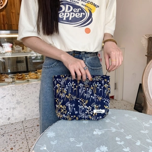 Macro detail of navy floral embroidery on high-quality fabric cosmetic storage bag