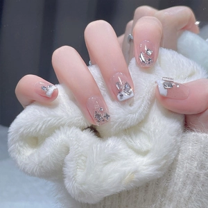 Macro detail of French tip press-on nails with rhinestones on soft white faux fur