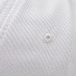Detailed close-up of white cotton baseball cap showing fabric texture and stitched eyelets