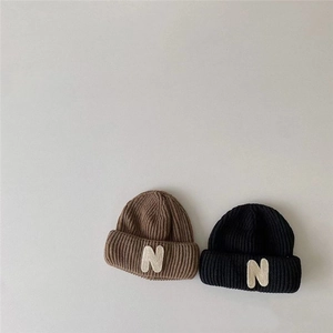 Detail showing the knitted texture and N patch on brown and black winter beanies