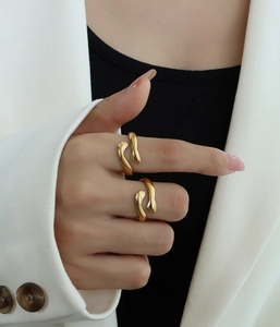Detail of stacked gold hugging hand rings on model finger showing metallic texture