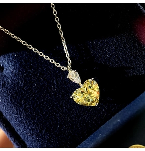 Macro shot of heart-shaped yellow zircon pendant on silver chain over blue velvet