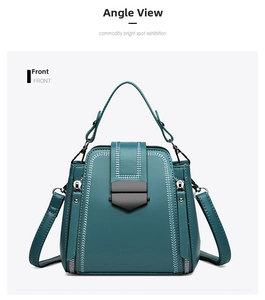 Front view of a teal soft leather handbag with white stitching and metal shield buckle