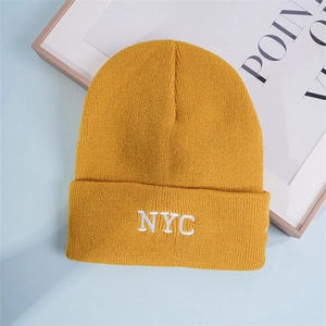 Detail of yellow knit beanie featuring thick cuff and white NYC letter embroidery