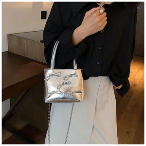 Detail of silver handbag with 3D bow decorations and metallic finish chain strap