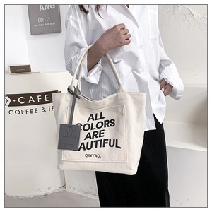 Detail of cream canvas tote bag featuring ALL COLORS ARE BEAUTIFUL printed text design