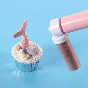Manual cake airbrush tool with brown glitter for cupcake decorating on blue background