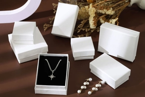 Macro view of white square and rectangular jewelry gift boxes with pearl earrings