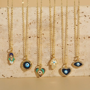 Golden Evil Eye and Hamsa Hand pendant necklaces set with blue zircon accents